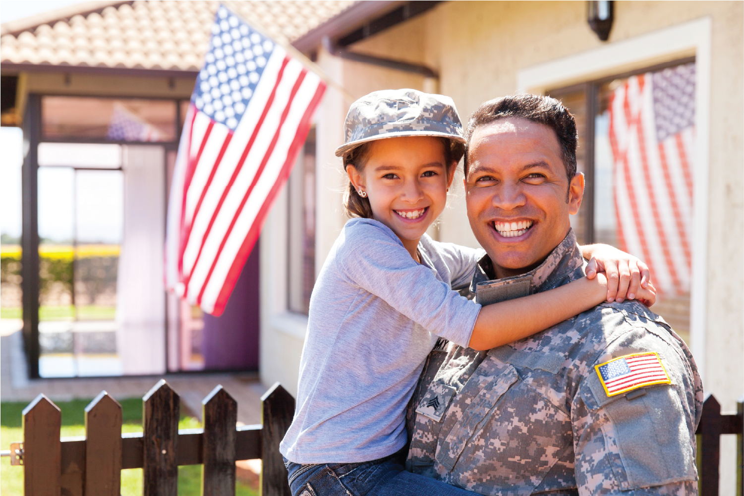 Veteran family smiling at the camera with US flags behind them