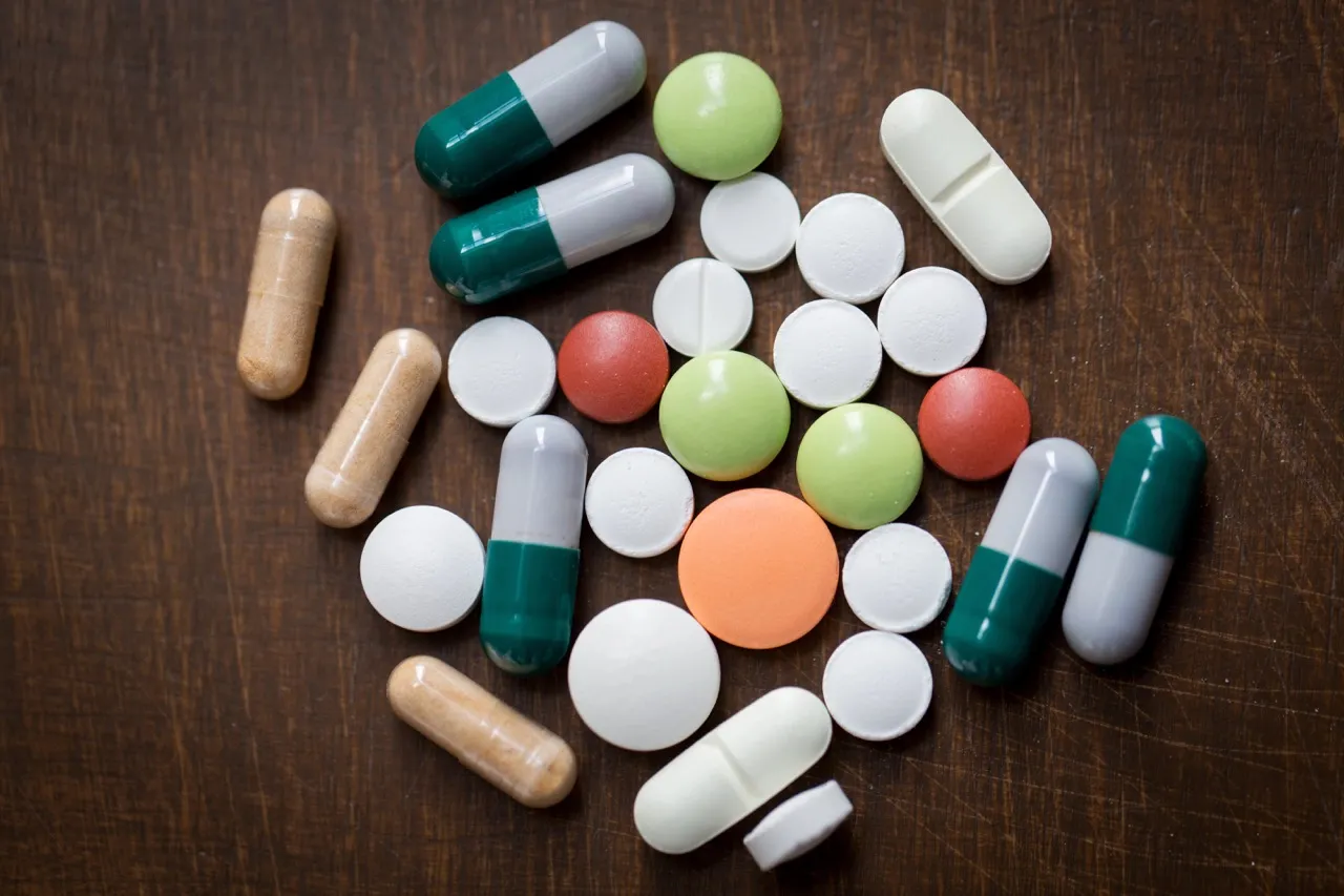 Assorted pills and capsules on a wooden table