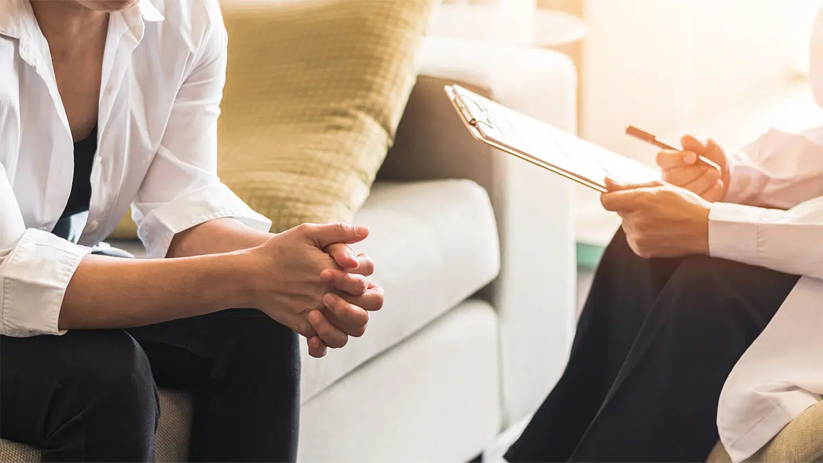 Image of woman clasping hands in therapy. Studies show that MAT for opioid use disorder reduces overdose deaths by 50 percent or more