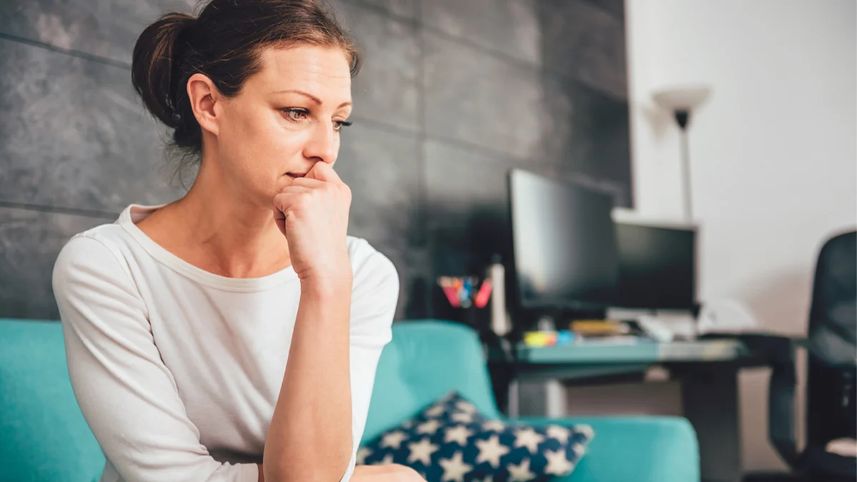 Woman sitting with her hand covering her mouth.