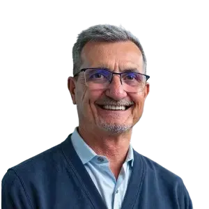 A headshot of a smiling man with gray hair and glasses wearing a blue button-down shirt.